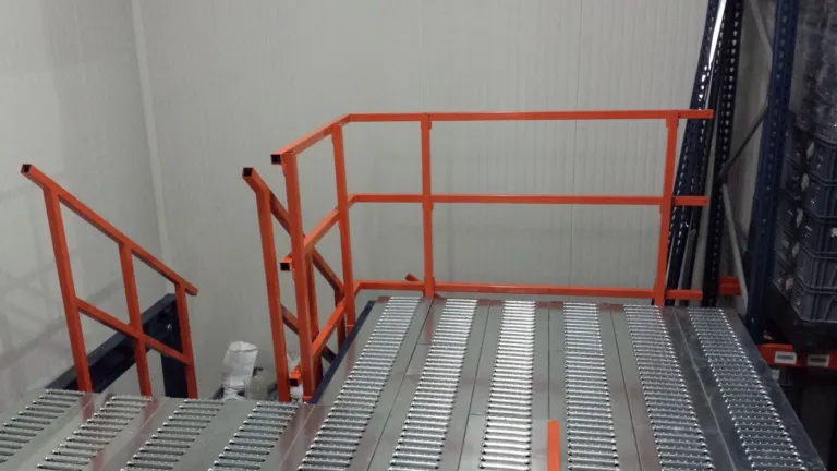 Entreplanta sobre racks en cuarto frío con escalera y barandas